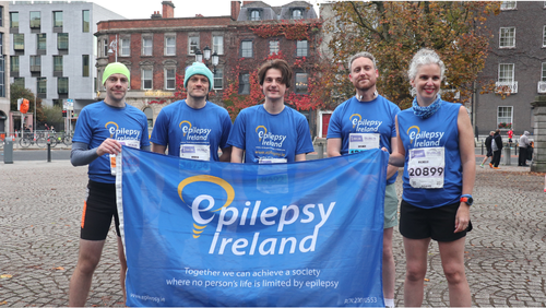 Five people in Epilepsy Ireland shirts holding an Epilepsy Ireland flag