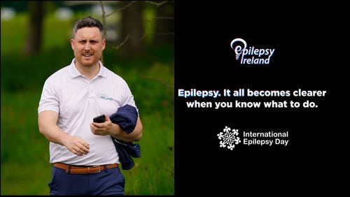 Daragh to the LHS of the picture with EI Logo and message: Epilepsy, it all becomes clearer when you know what to do on a black background with International Epilepsy Day logo at bottom