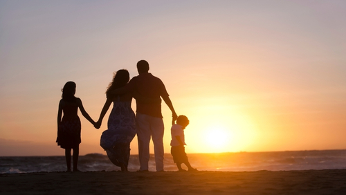 Family holding hands looking at a sunset