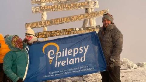 Mark McGuire holding Epilepsy Ireland flag on top of Kilimanjaro 