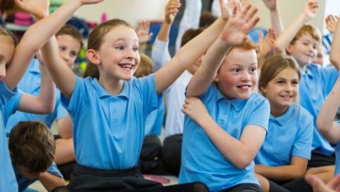 Children in school uniform raising their hands