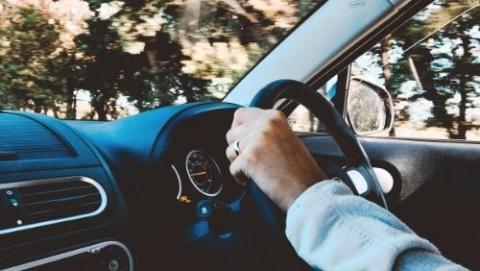 person holding steering wheel and driving car.