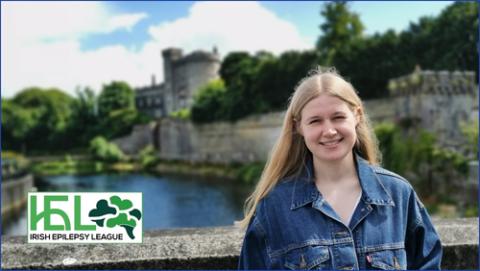 Evie Dickinson standing in front of a river and Irish Epilepsy League logo in LHS