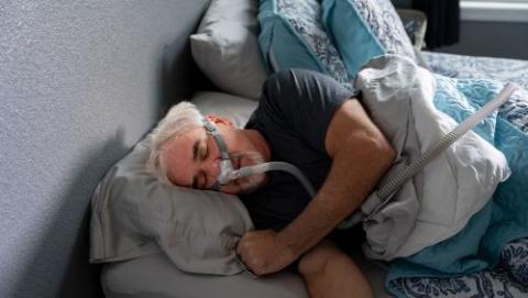 Man lying in bed with Sleep Apnoea breathing device on